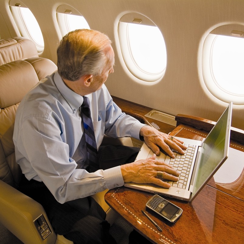 old man working on a lapton in a plane